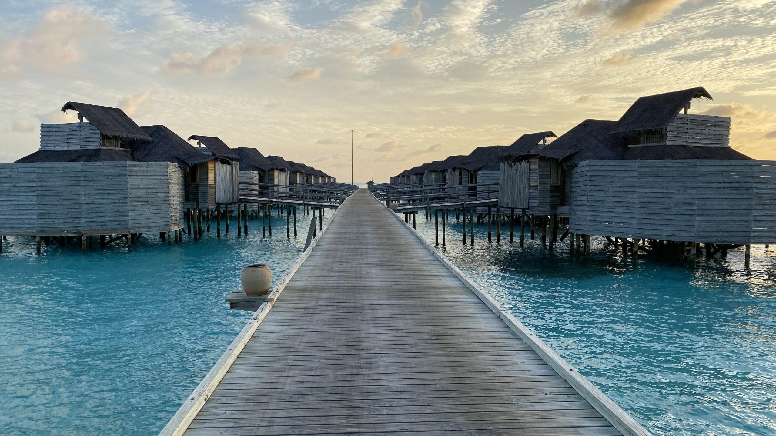 a wooden walkway leading to a row of huts on stilts