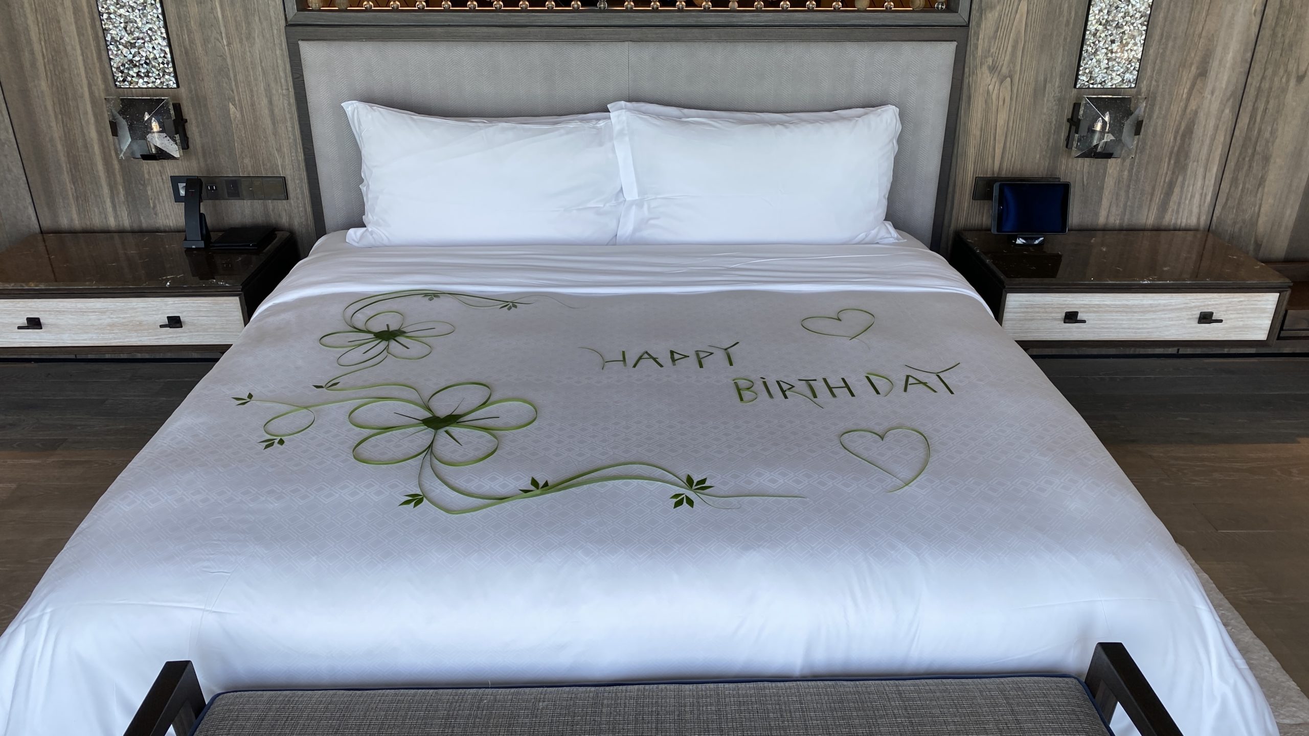a bed with a white sheet with green flowers and hearts