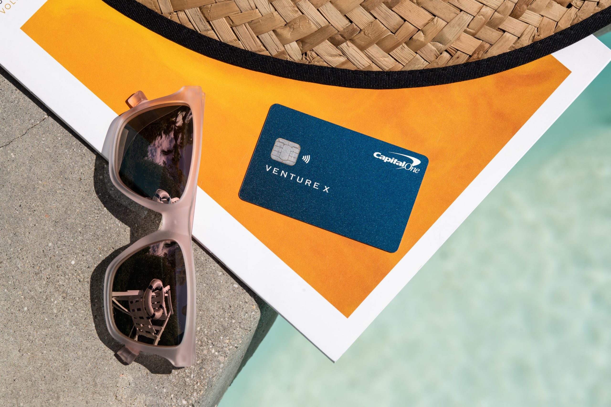 a credit card and sunglasses on a stone surface