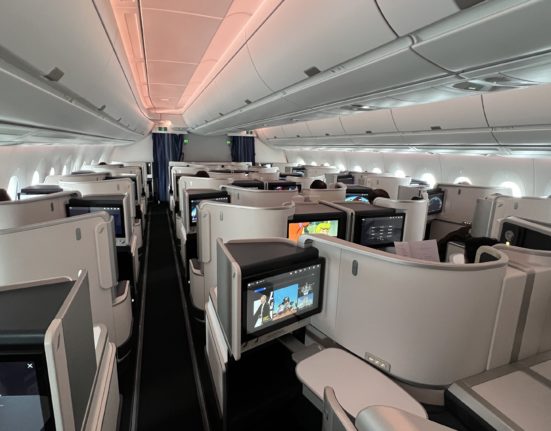 a row of seats with monitors and a tv in the middle of the aisle