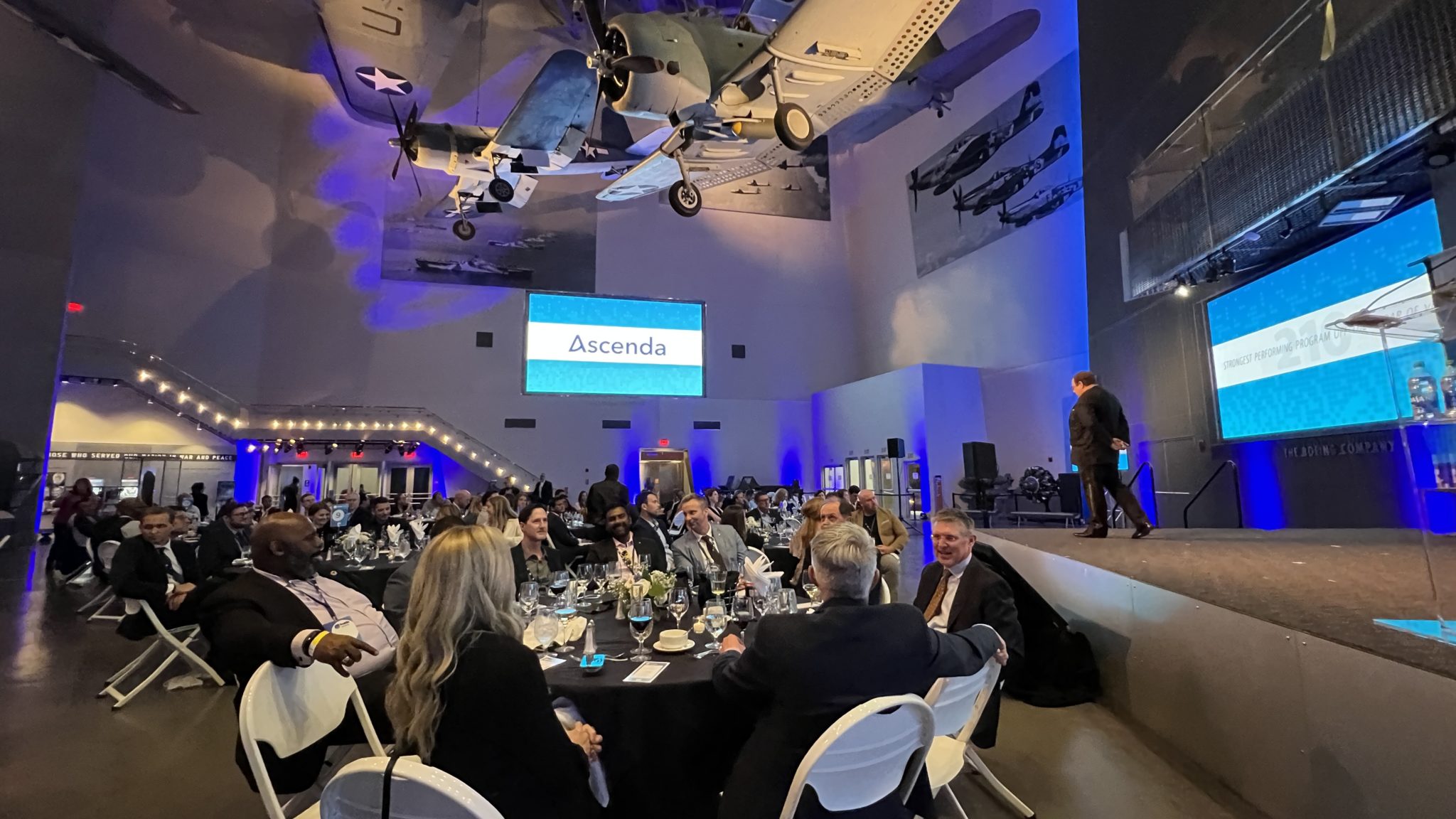 a group of people sitting at a table in a room with a plane from the ceiling