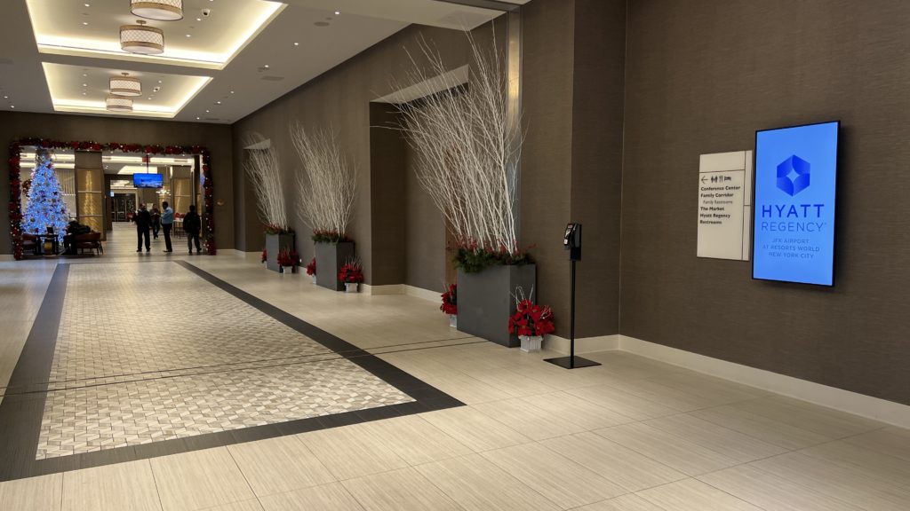 a hallway with white branches in pots