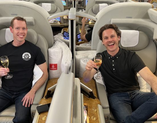 two men sitting in chairs on an airplane