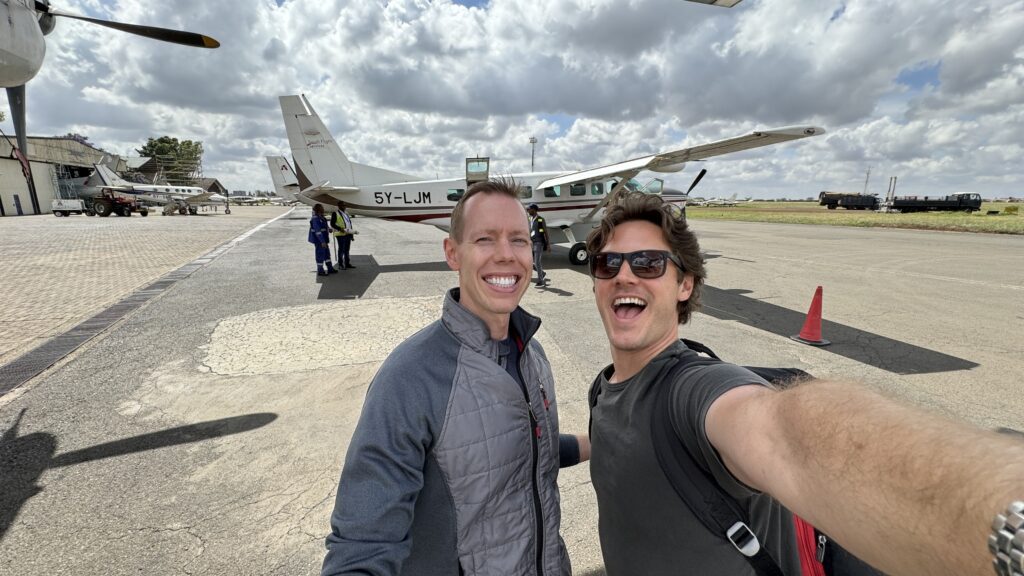 two men taking a selfie in front of an airplane