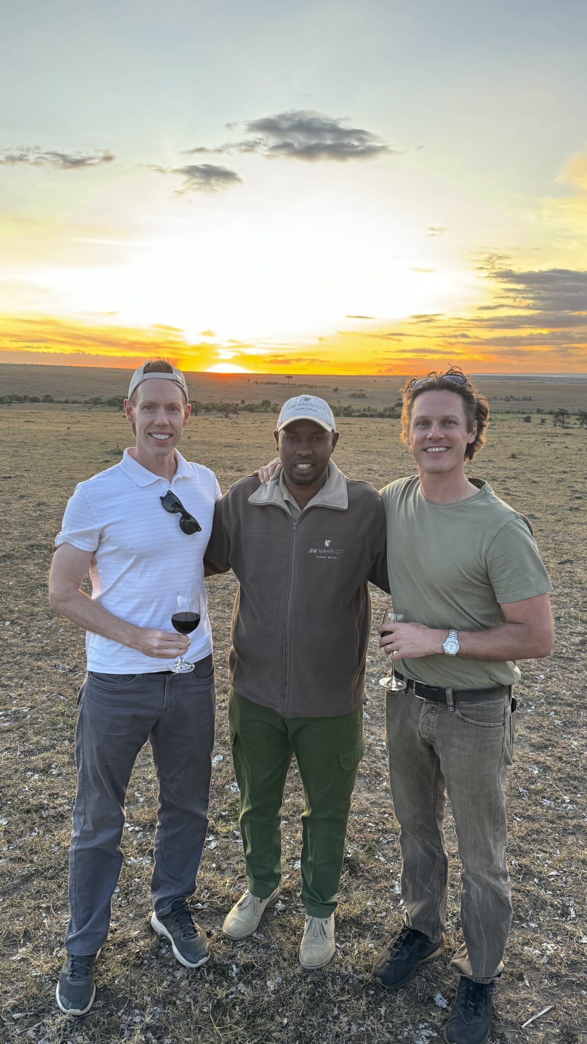 a group of men standing in a field with a sunset behind them