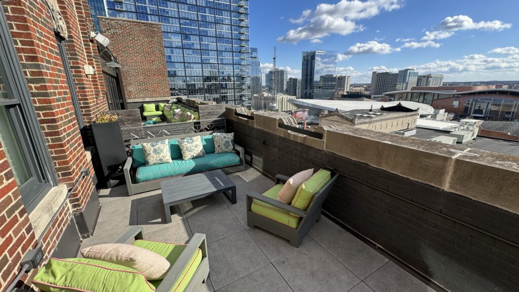 a rooftop patio with chairs and tables and a city skyline