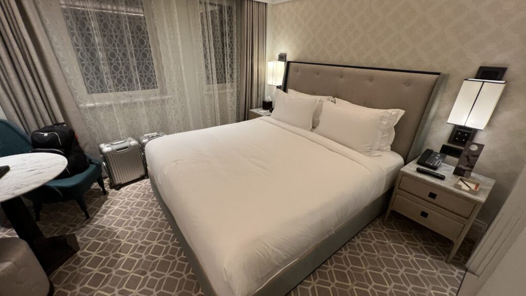 a bed with white sheets and pillows in a hotel room
