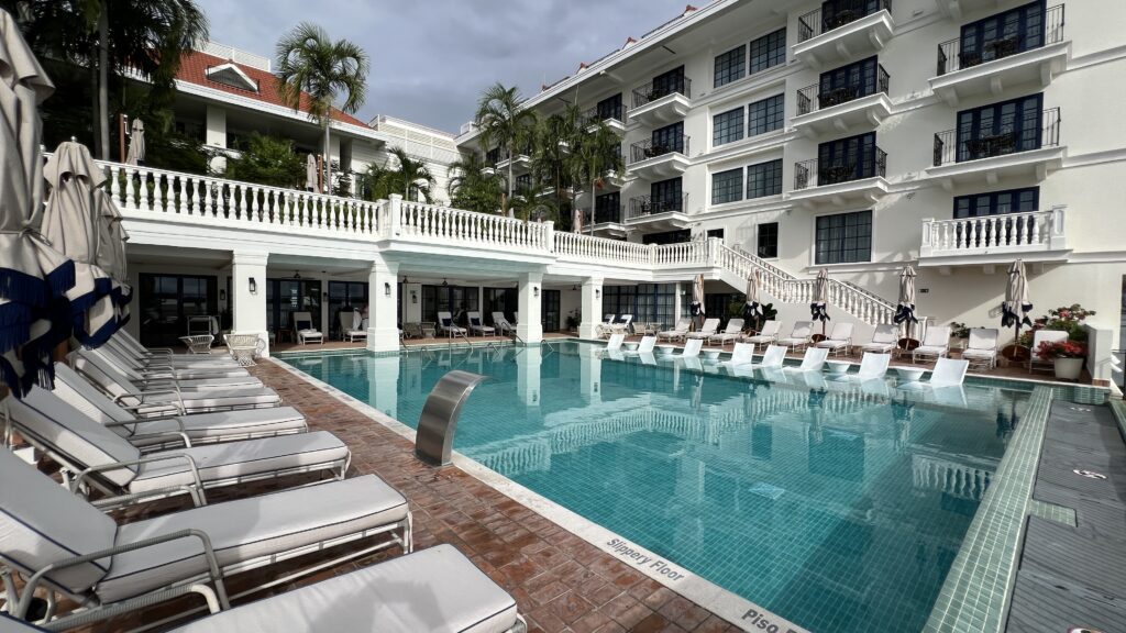 a pool with chairs and a building in the background